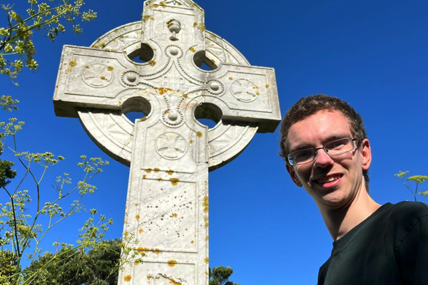 Jamie standing next to a large stone cross.